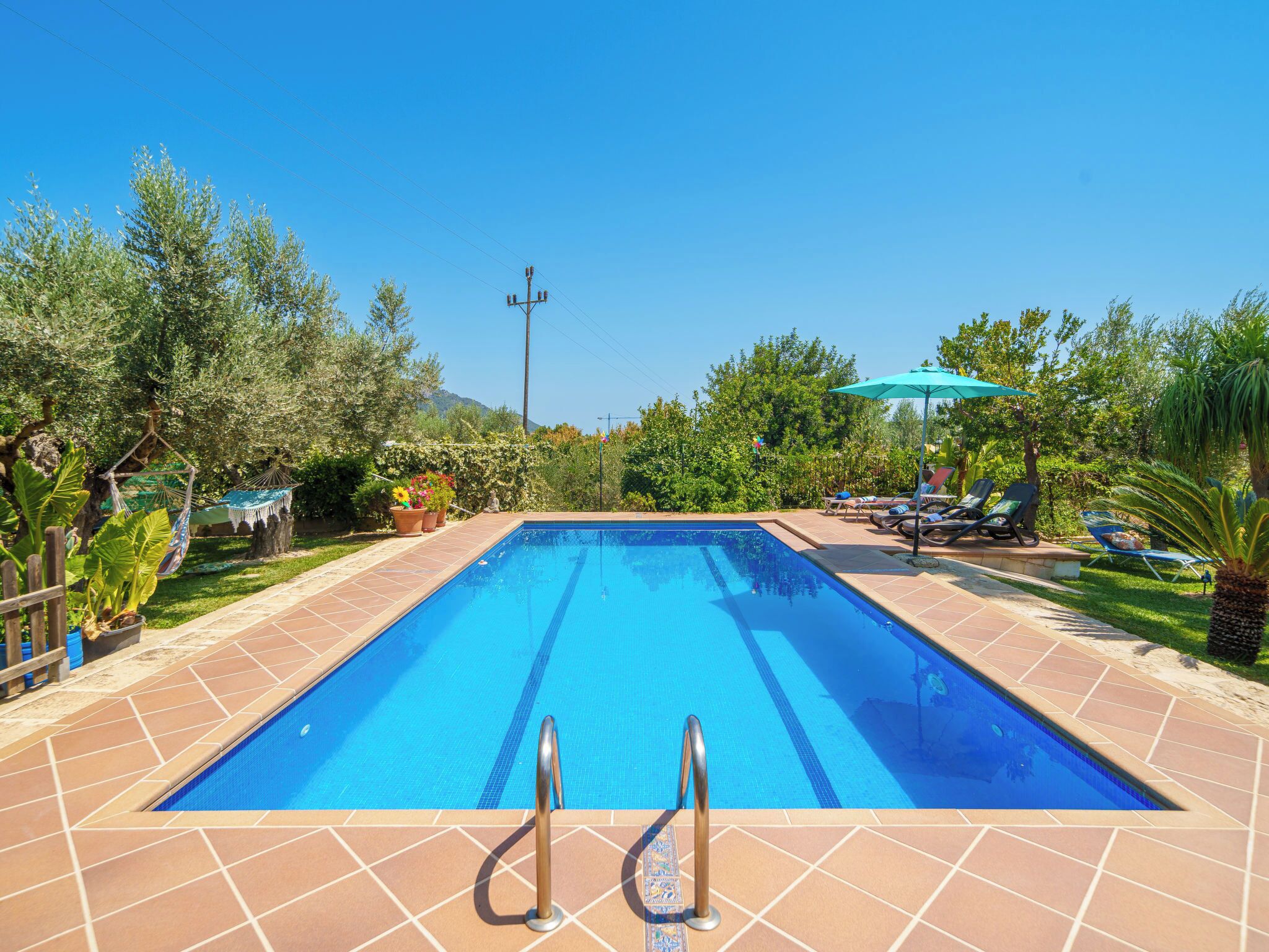 A rectangular swimming pool with clear blue water, surrounded by a tiled deck.