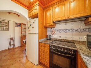 Eine Küche mit Holzausstattung, einem weißen Kühlschrank, einem Herd und einer gefliesten Spritzwand.