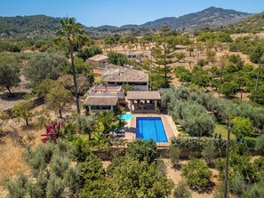 Eine Villa mit Swimmingpool, umgeben von Bäumen und Hügeln.