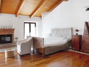 A bedroom with a wooden ceiling, a bed with a canopy, a fireplace, and a wooden cabinet. - Sweet Life by Interhome (Priocca)