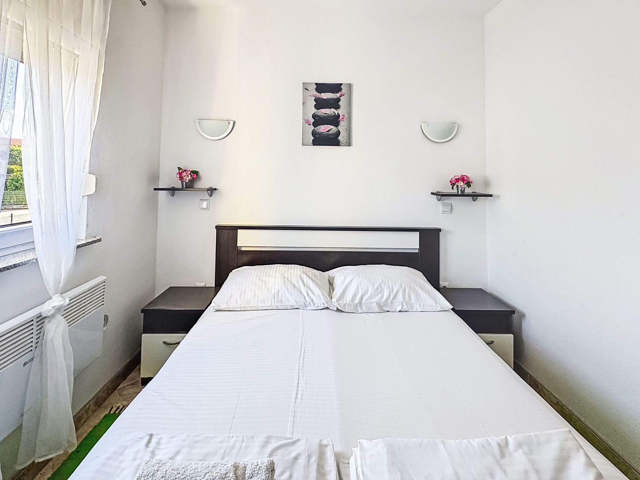 A neatly arranged bedroom with a bed, bedside tables, and wall-mounted lamps.