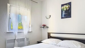 A neatly made bed with white linens and towels, a bedside table with a vase of flowers, and a window with sheer curtains. - Rondine by Interhome (Novigrad (Istra))