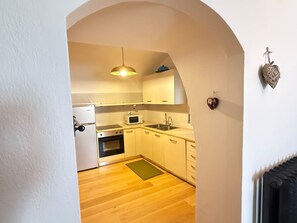 A kitchen with a microwave, stove, sink, and hanging light fixture. - Casa Le Pale by Interhome (Fiera di Primiero)