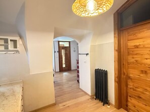 A hallway with a wooden door, a radiator, and a ceiling light fixture. - Casa Le Pale by Interhome (Fiera di Primiero)
