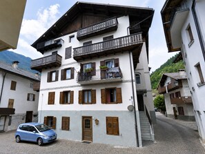 A multi-story building with balconies, a car parked in front, and a cobblestone street. - Casa Le Pale by Interhome (Fiera di Primiero)