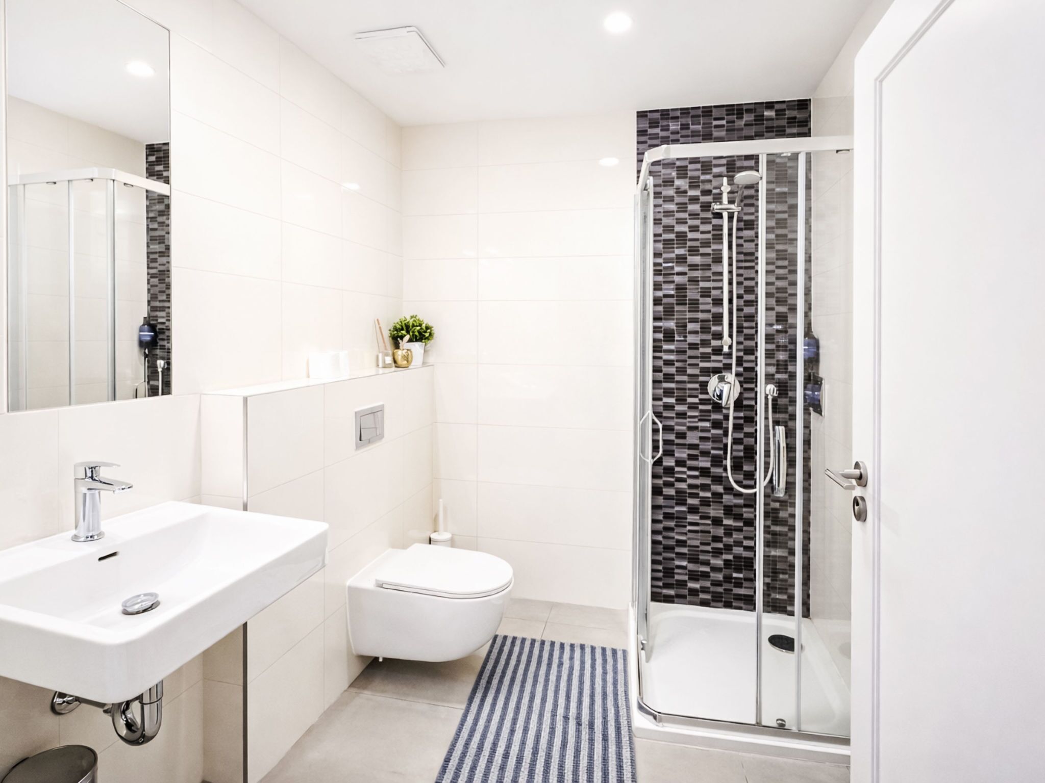 A modern bathroom with a glass-enclosed shower, a white sink, and a toilet.