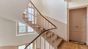 Uma escada espiral com corrimão, uma porta com puxador e uma janela com vista para o exterior.
