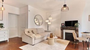 Uma sala de estar moderna com sofá, lareira, televisão e espaço de jantar.