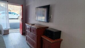 A room with a wooden dresser, a television mounted on the wall, and a small cabinet. - Mountain Inn (Gatlinburg)