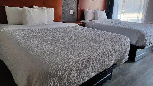 Two beds with headboards, a nightstand, and a window with curtains. - Mountain Inn (Gatlinburg)