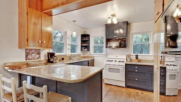 A kitchen with a central island, wooden cabinets, a stove, and a sink.