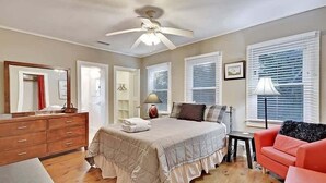 A bedroom with a bed, dresser, nightstand, and a ceiling fan.