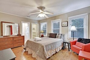 Ein Schlafzimmer mit Bett, Schminktisch, Nachttisch und Deckenventilator.