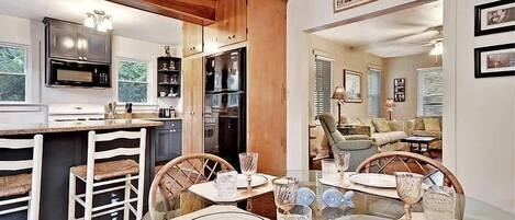 Una cocina moderna con armarios de madera, un comedor con una mesa preparada para cuatro personas y vistas al salón.