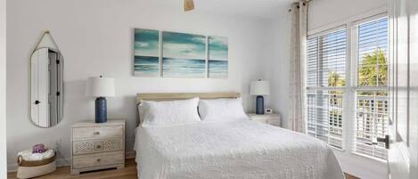 Een slaapkamer met een bed, twee nachtkastjes, een plafondventilator, een raam met jaloezieën en een spiegel aan de muur.
