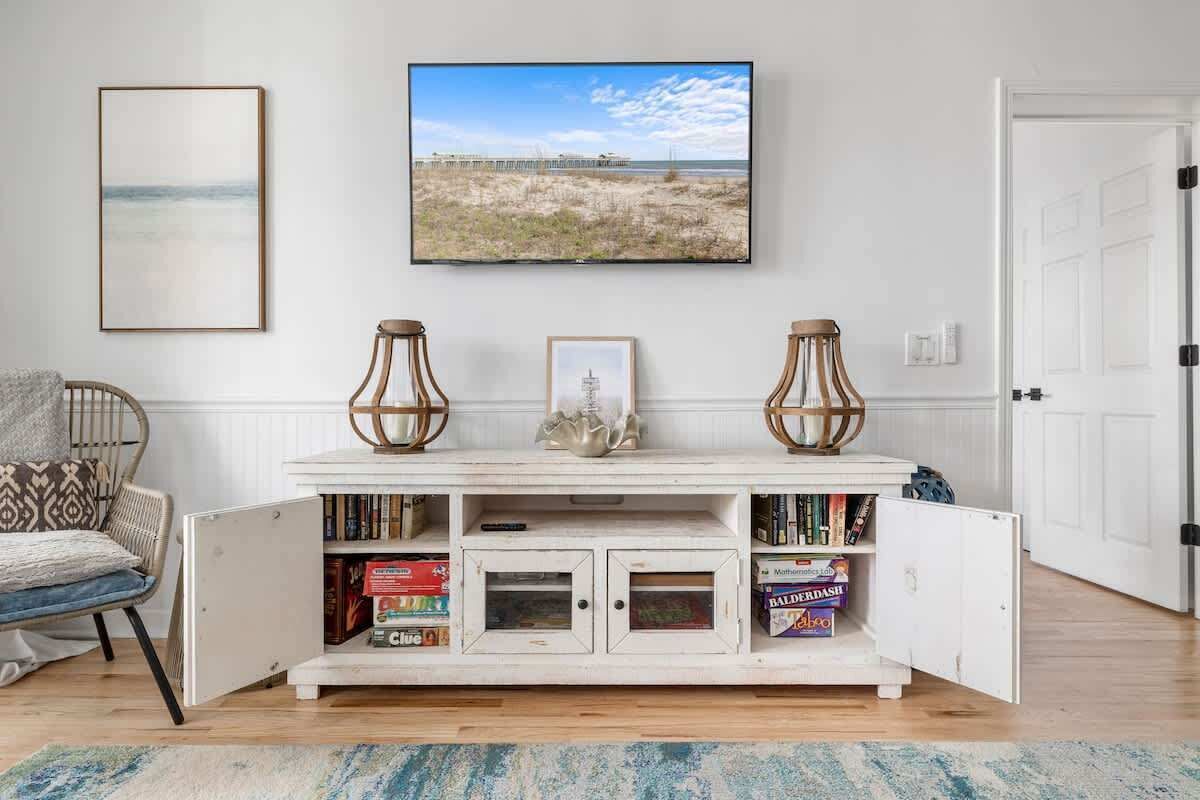 Een witte console tafel met boeken, een lijst met afbeelding en twee decoratieve vazen.