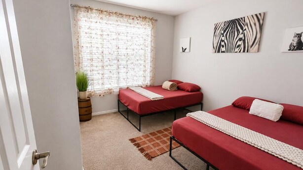 A room with two beds, a window with curtains, a plant, and artwork on the wall. - Pleasant 3-bedroom house with AC in charming Odessa, maximum guest 6. (Odessa)