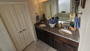 Un baño con dos lavamanos, un espejo grande y una ventana.