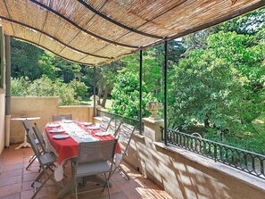 An outdoor dining area with a table set for four, surrounded by chairs, under a shaded pergola. - Chateau Payan by Interhome (Flassans sur Issole)