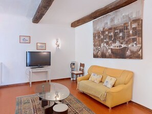 A living room with a TV, sofa, and a painting of boats. - Chateau Payan by Interhome (Flassans sur Issole)
