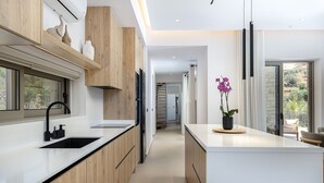 Eine moderne Küche mit Holzschränken, einem schwarzen Spülbecken und einem Orchideenstrauß.