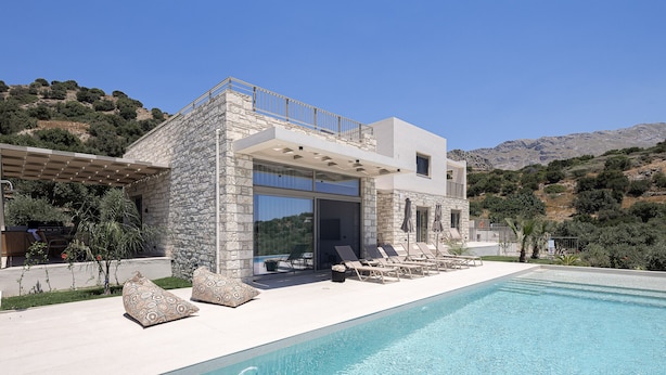 Ein modernes Haus mit Pool, Natursteinfassade und Blick auf die Hügel.