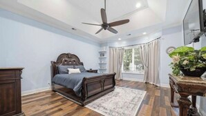 A bedroom with a bed, a ceiling fan, a TV, a window with curtains, and a plant. - Fantastic 4-bedroom house with AC in tranquil Cordova (Cordova)