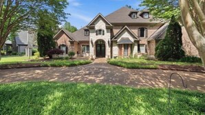 A two-story house with a stone facade, a front porch, and a driveway. - Fantastic 4-bedroom house with AC in tranquil Cordova (Cordova)