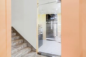 Portaat johtavat huoneeseen, jossa on lasiovi. Ovessa on kyltti, jossa lukee ”AG & NON AG ROOM”, ja huoneesta on näkymä sisätiloihin.