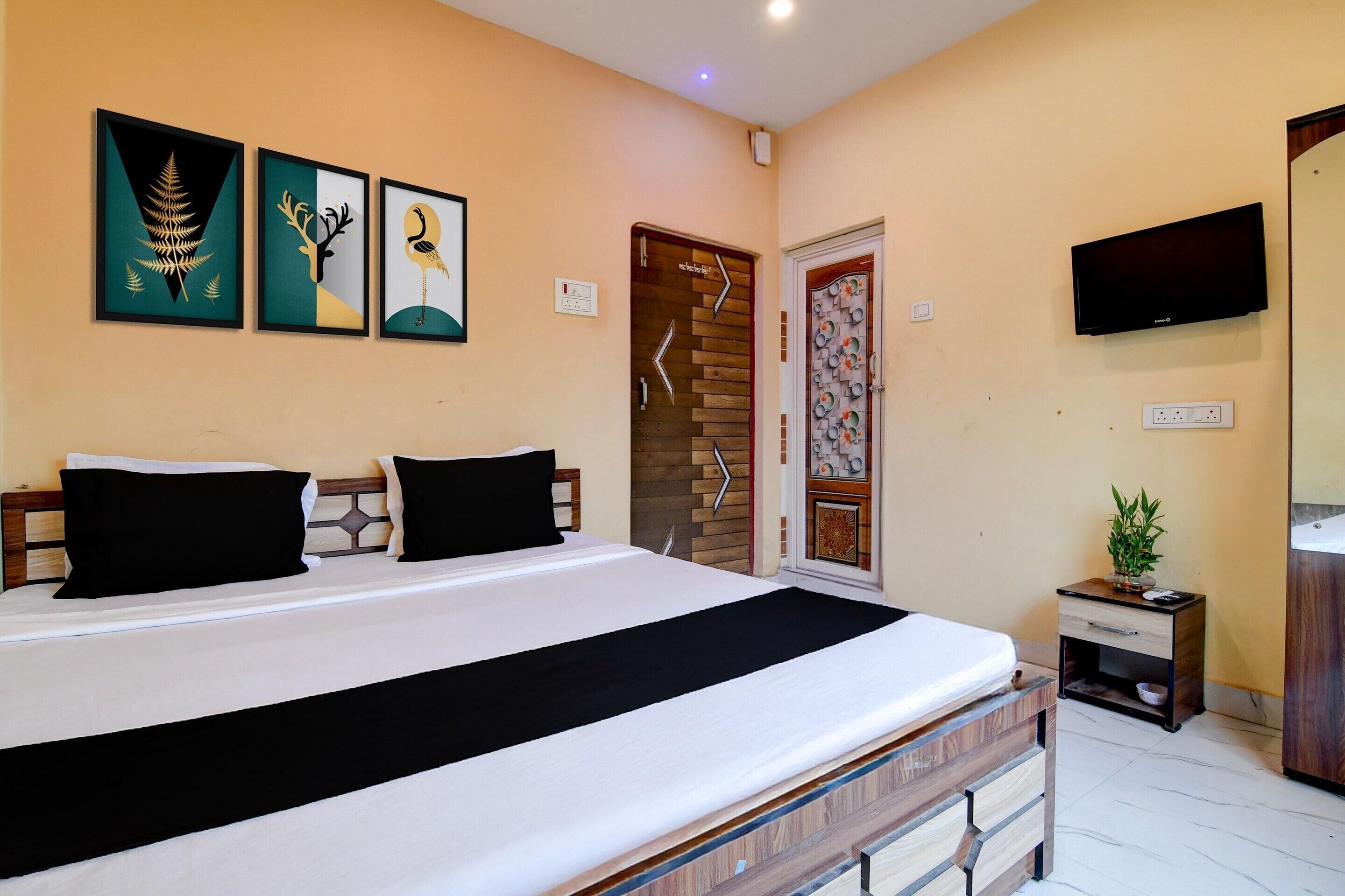 A hotel room with a bed, a TV, and artwork on the wall.
