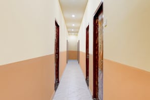 Um corredor com portas em ambos os lados, soalho em azulejos e parede de cor clara.