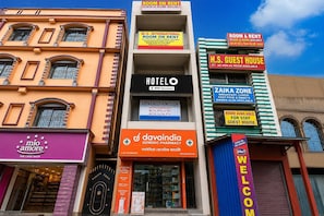 A hotel with multiple signs advertising room and guest house availability, a sign for a generic pharmacy, and a cake shop. - Deluxe Room Chowdhury Guest House (Barakpur)