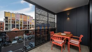 Ein Balkon mit Tisch und Stühlen, Blick auf Gebäude und einem Ziergitter.