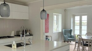 Uma cozinha moderna com ilha central, armários brancos e iluminação pendente.