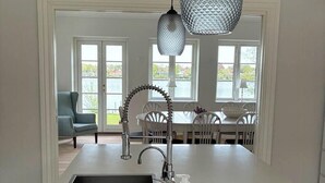 Cozinha com ilha central, pia e torneira. Duas luminárias pendentes sobre a ilha.