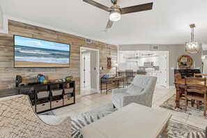 Ein modernes Wohnzimmer mit Fernseher, Deckenventilator und Essbereich mit Holztisch und Stühlen.