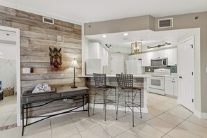 Eine moderne Küche mit weißen Schränken, einer Edelstahl-Mikrowelle und einer Wand mit Holzpaneelen.