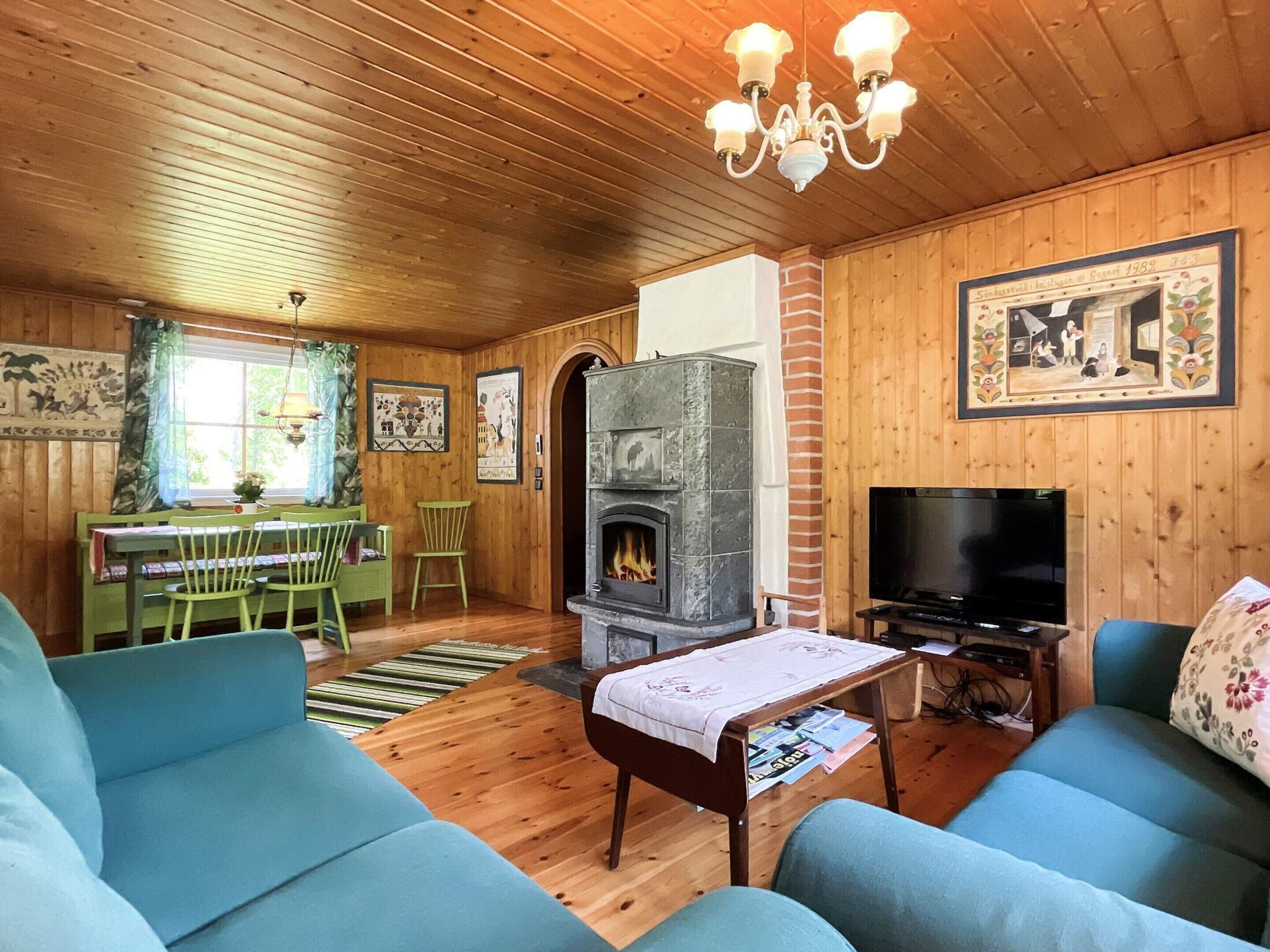 A cozy living room with a fireplace, a television, and green furniture.