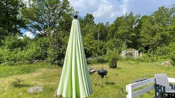 A deck with a green umbrella, a barbecue grill, and a wooden fence.