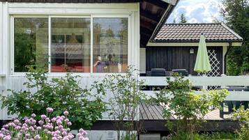 A wooden house with large windows, a balcony, and a green umbrella.