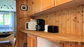 Una cocina de madera con microondas, cafetera y un reloj en la pared.