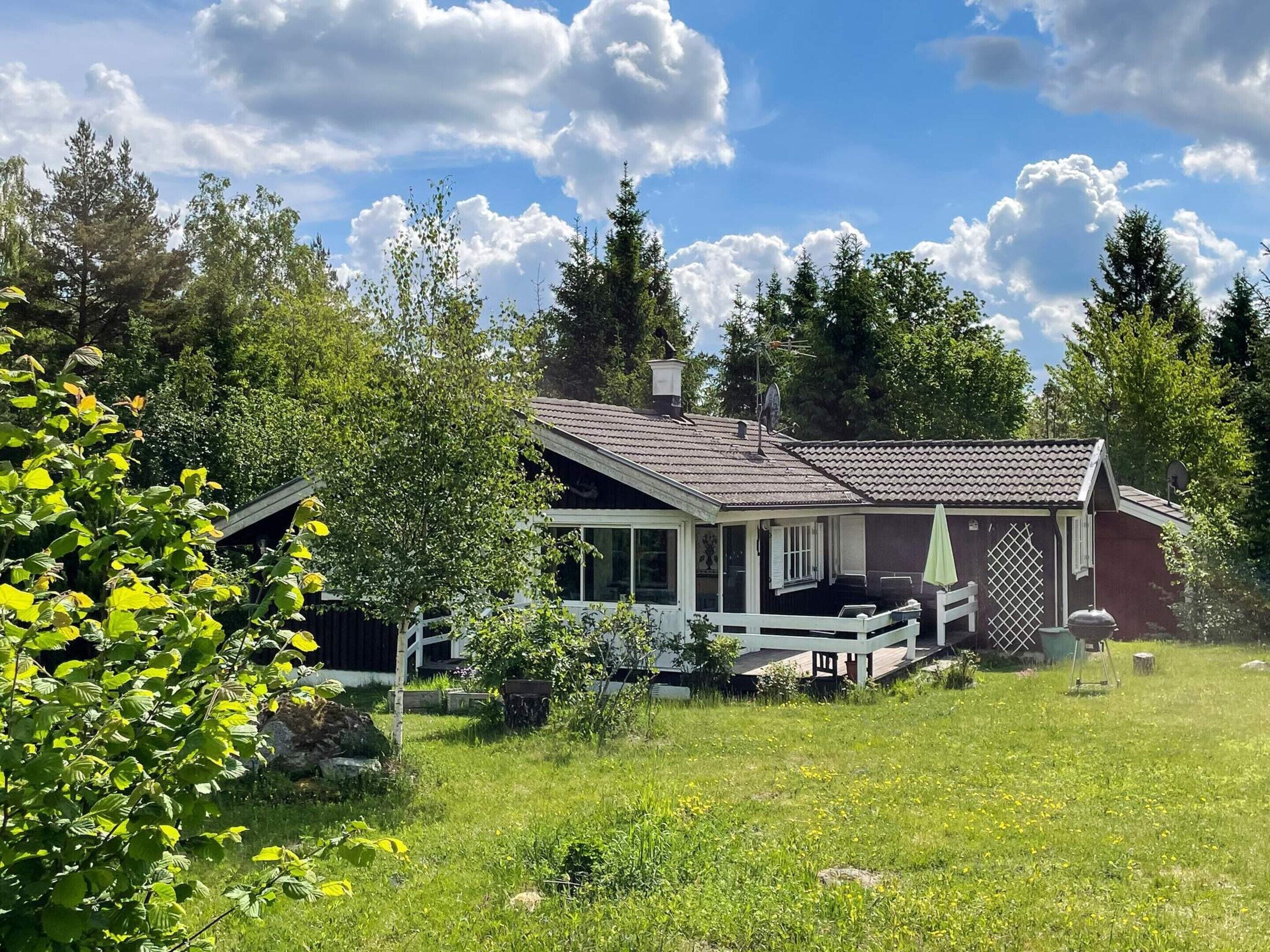 A house with a porch, a fenced yard, and a clear sky.