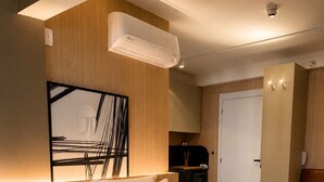 Un dormitorio moderno con una cama grande, un aire acondicionado de pared, un armario de madera y una puerta que da al baño.