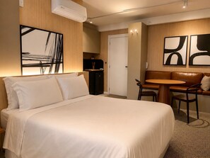 Ett hotellrum med en säng, ett skrivbord, en stol, ett litet bord och en soffa.