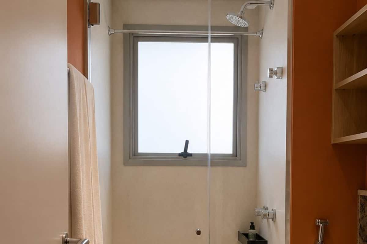 Ein Badezimmer mit Glastür, Fenster, Toilette und Dusche.