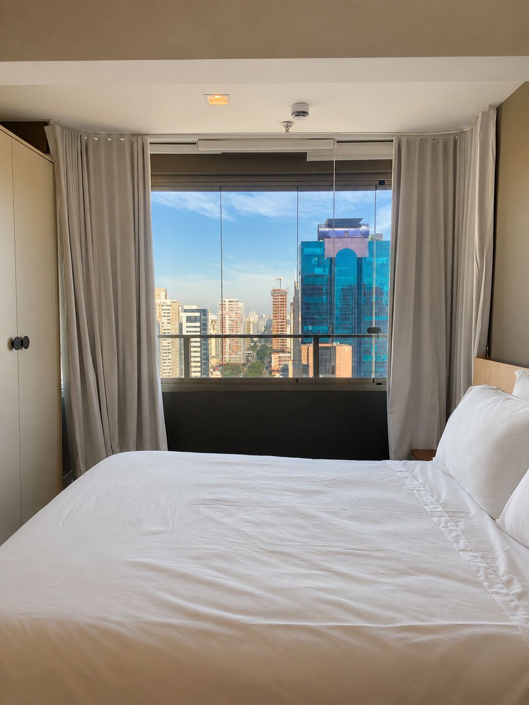Ett hotellrum med en stor säng, utsikt över staden och en modern design.
