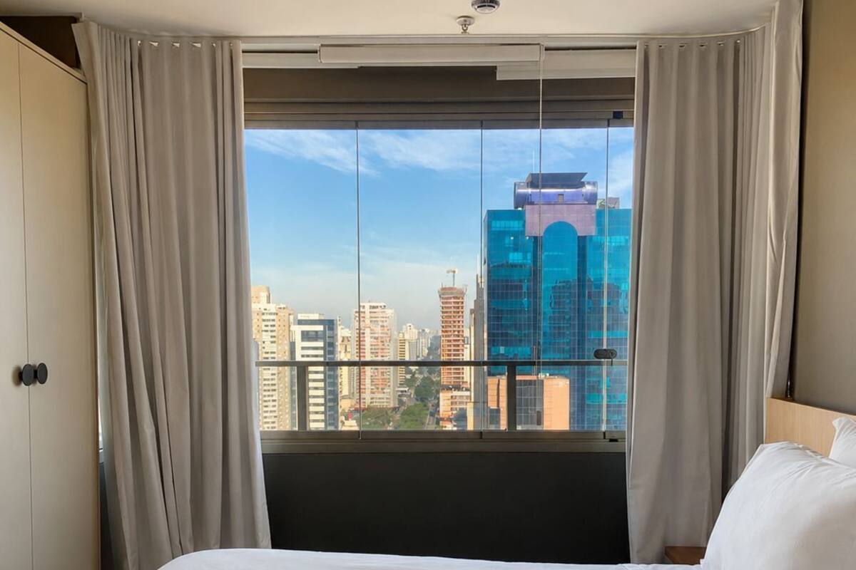 Ein Hotelzimmer mit einem großen Bett, Blick auf die Stadt und einem modernen Design.