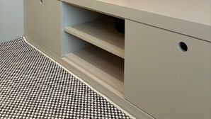 Una habitación moderna con un sofá de cuero marrón, un espejo grande, un escritorio con cajones y una alfombra estampada.