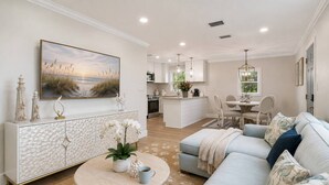 Un salon moderne avec un canapé bleu clair, une table basse ronde et un tableau représentant une scène de plage.
