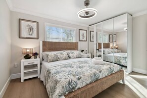 Ein Schlafzimmer mit einem großen Bett, einem Nachttisch, einer Lampe, einem Spiegel und gerahmten Bildern an der Wand.